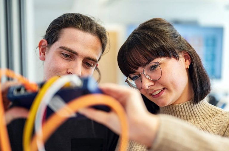 Zwei Auszubildende sitzen schauen sich ein Netzwerk-Hub an.
